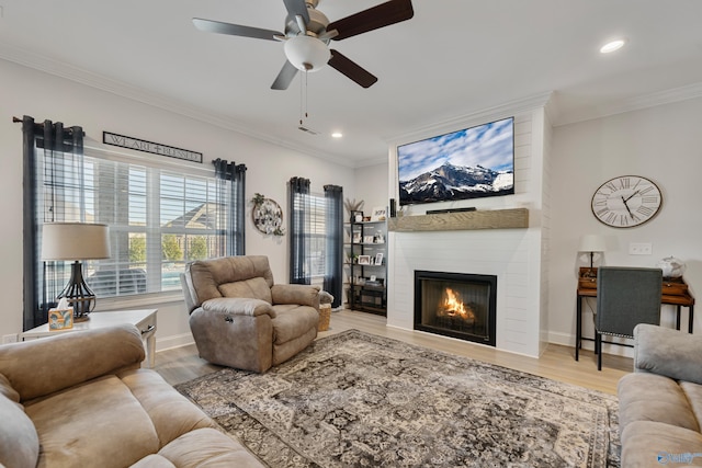 living room featuring a fireplace, light wood-type flooring, ceiling fan, and crown molding