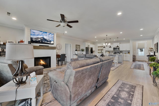 living room featuring a fireplace, light hardwood / wood-style floors, ceiling fan, and crown molding