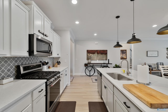 kitchen featuring decorative backsplash, appliances with stainless steel finishes, sink, decorative light fixtures, and white cabinetry