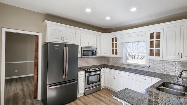 kitchen with appliances with stainless steel finishes, sink, white cabinets, and dark stone counters