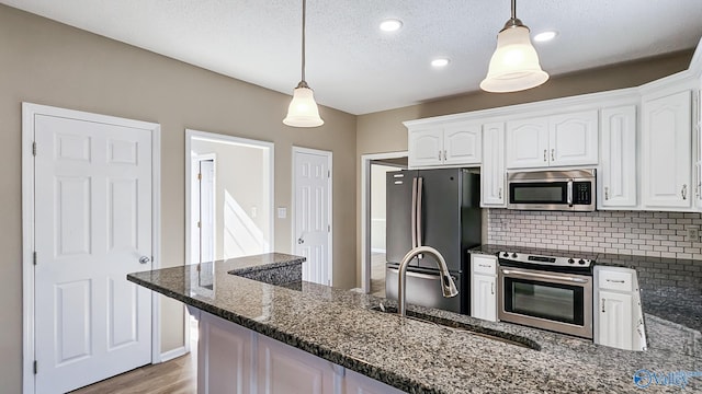 kitchen with stainless steel appliances, white cabinets, and decorative light fixtures