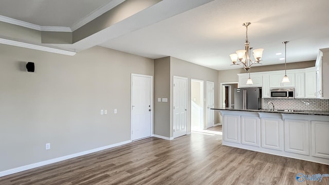 kitchen featuring pendant lighting, light hardwood / wood-style flooring, backsplash, stainless steel appliances, and white cabinets