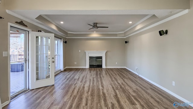 unfurnished living room featuring wood-type flooring, ornamental molding, a raised ceiling, and ceiling fan