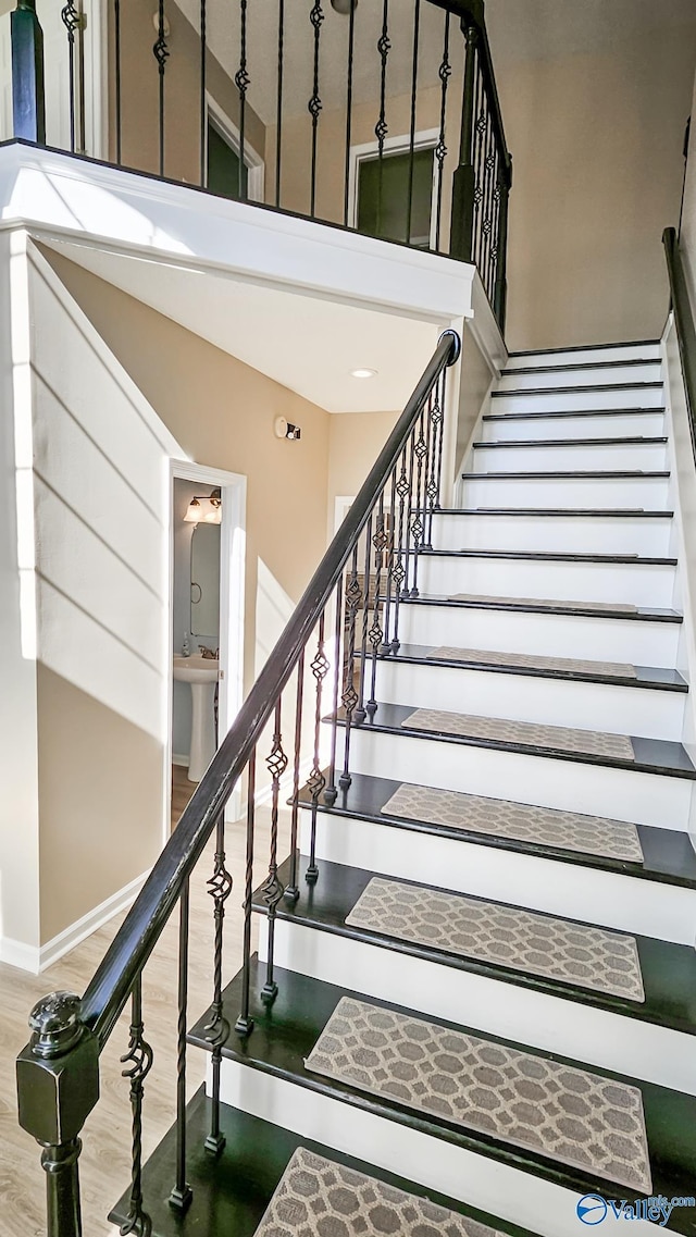 stairs with a towering ceiling and wood-type flooring