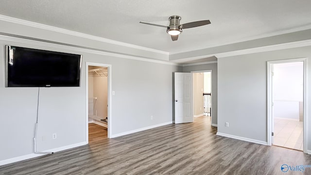 unfurnished bedroom with connected bathroom, wood-type flooring, a spacious closet, crown molding, and a textured ceiling