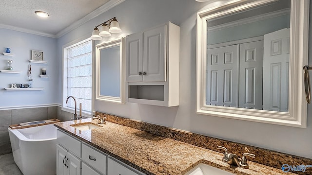 bathroom with vanity, ornamental molding, a tub, and a textured ceiling