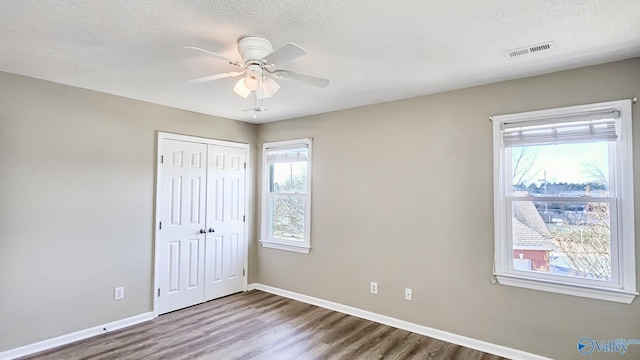 unfurnished bedroom with ceiling fan, wood-type flooring, a closet, and a textured ceiling