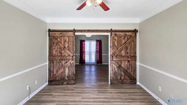 foyer with dark wood-type flooring, ceiling fan, a barn door, and crown molding