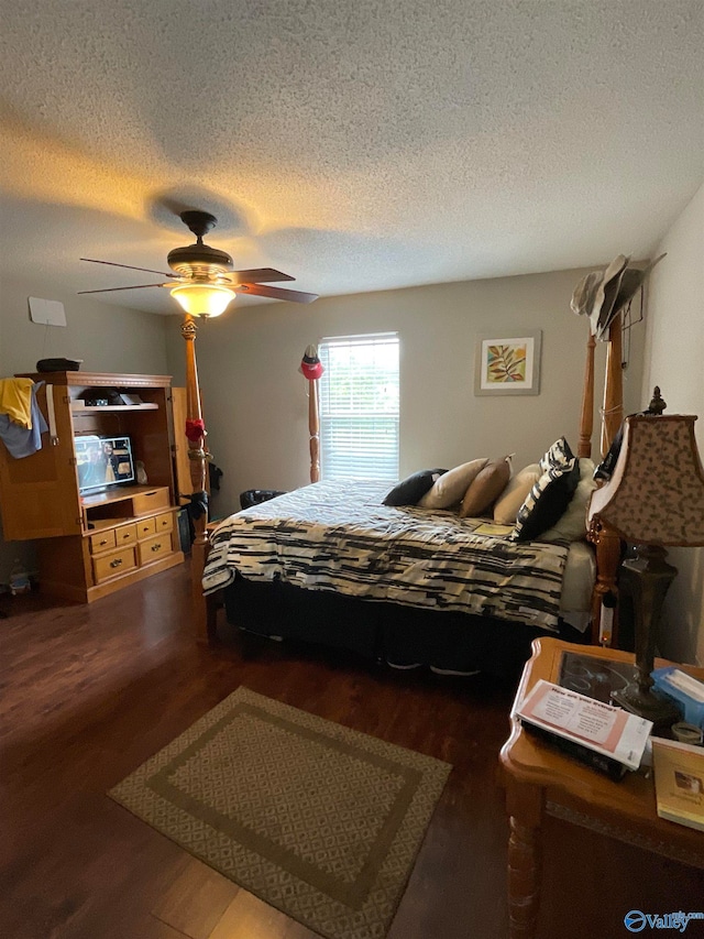 bedroom with ceiling fan, a textured ceiling, and dark hardwood / wood-style floors