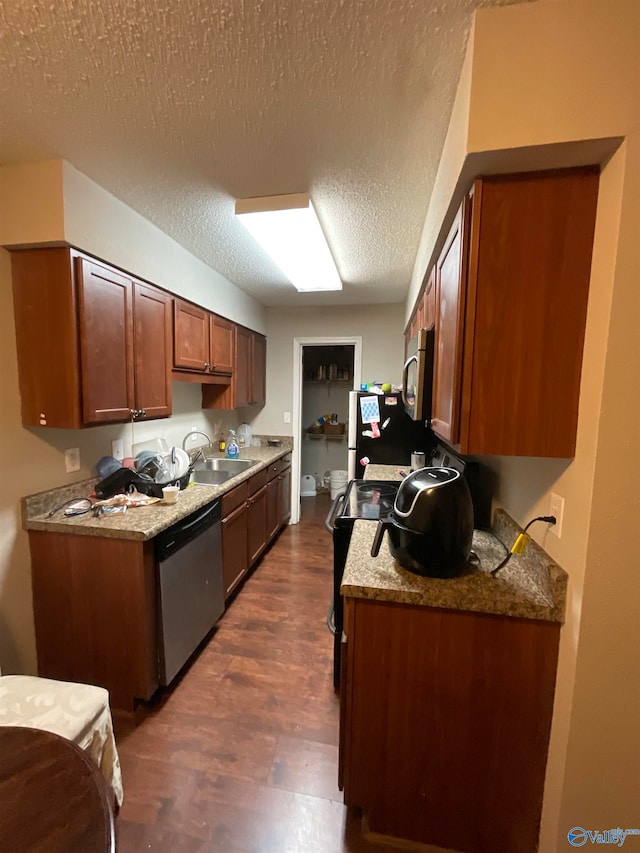 kitchen with light stone counters, a textured ceiling, sink, stainless steel appliances, and dark hardwood / wood-style flooring