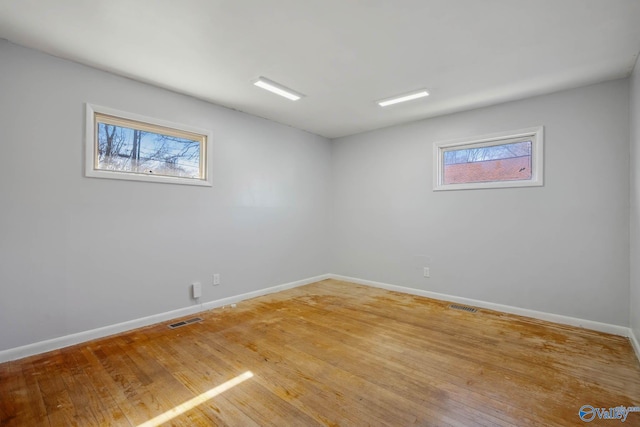 empty room featuring visible vents, light wood-style flooring, and baseboards