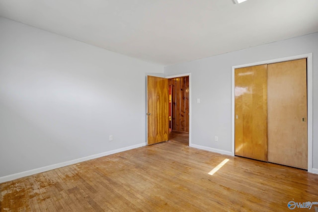 unfurnished bedroom featuring a closet, wood finished floors, and baseboards