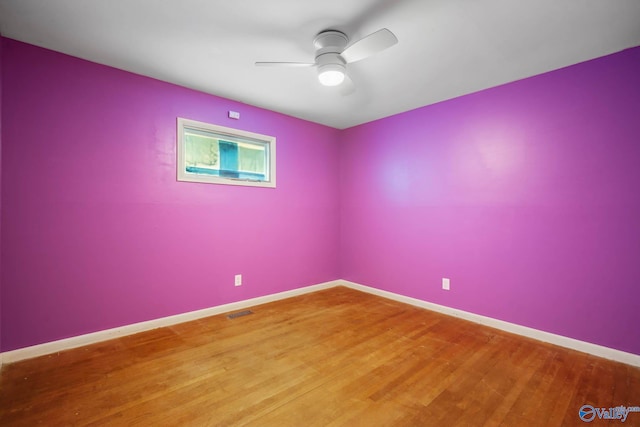 unfurnished room with a ceiling fan, visible vents, baseboards, and wood finished floors