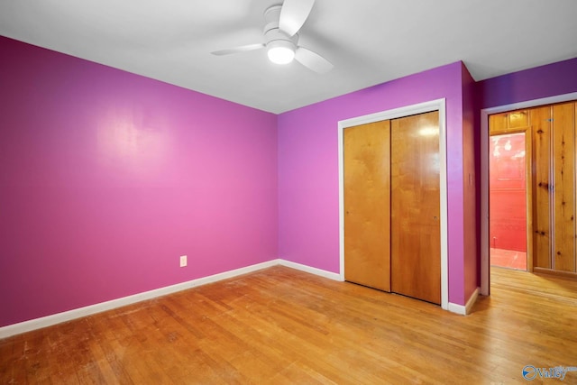 unfurnished bedroom featuring a ceiling fan, a closet, baseboards, and wood finished floors