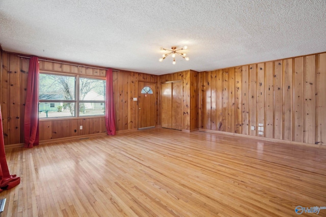 unfurnished living room with a textured ceiling, visible vents, light wood-style flooring, and baseboards