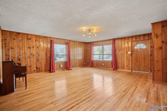 living area with a textured ceiling, light wood finished floors, and baseboards