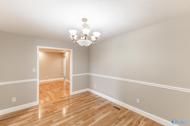 138 Singletree Dr, Hazel Green, AL 35750 - unfurnished room featuring visible vents, a notable chandelier, a textured ceiling, light wood finished floors, and baseboards