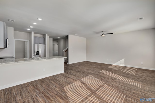 kitchen with stainless steel refrigerator with ice dispenser, sink, light stone counters, dark hardwood / wood-style flooring, and ceiling fan