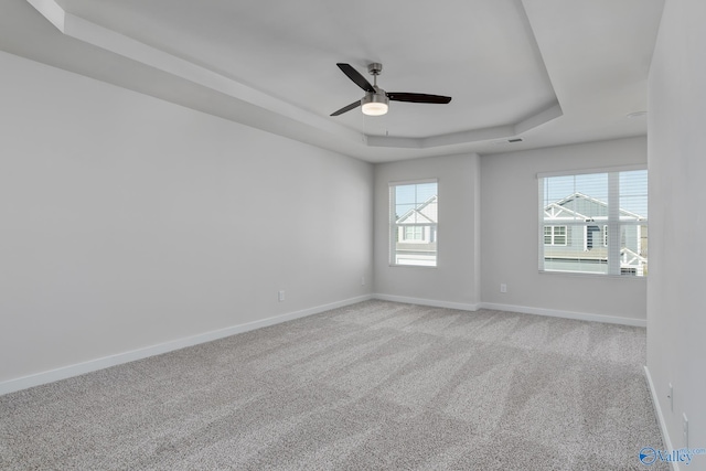 carpeted spare room featuring a raised ceiling and ceiling fan