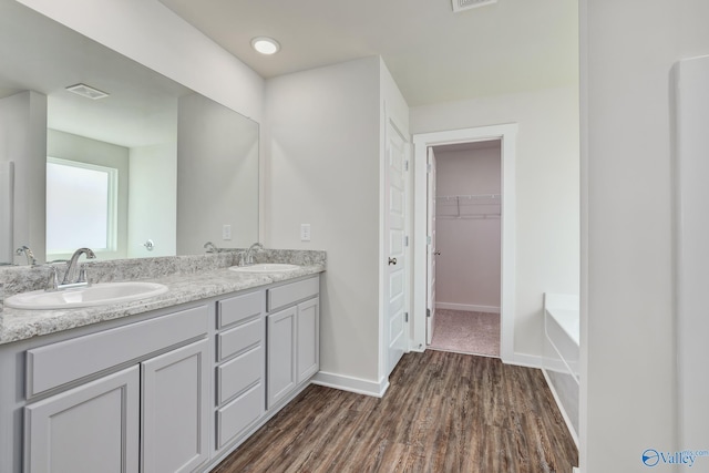 bathroom featuring hardwood / wood-style flooring, vanity, and a bath