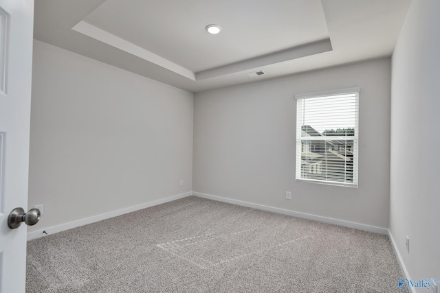 carpeted empty room with a tray ceiling