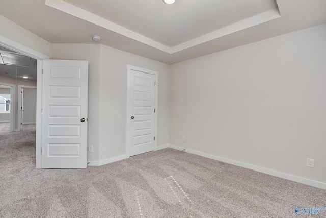 unfurnished bedroom featuring a tray ceiling and carpet flooring