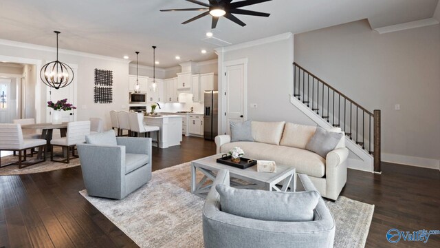 living room featuring ceiling fan with notable chandelier, dark hardwood / wood-style flooring, and ornamental molding