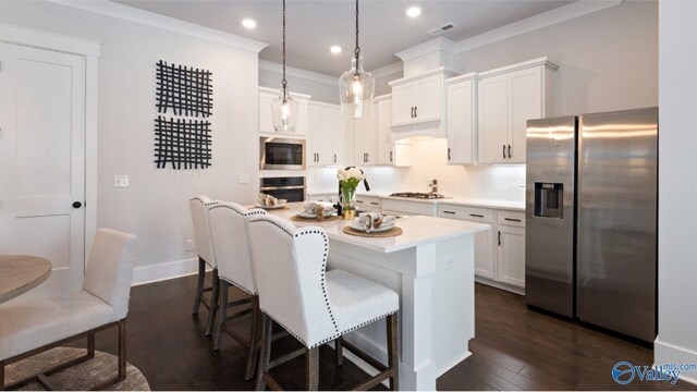 kitchen featuring dark hardwood / wood-style flooring, appliances with stainless steel finishes, a kitchen bar, hanging light fixtures, and a center island