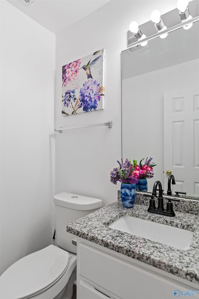 half bathroom with vanity and toilet