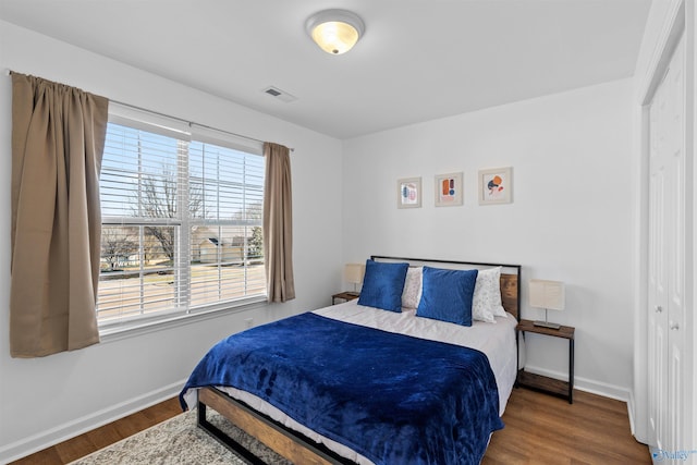 bedroom with visible vents, baseboards, and wood finished floors