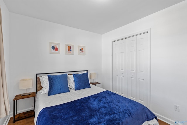 bedroom with wood finished floors, baseboards, and a closet