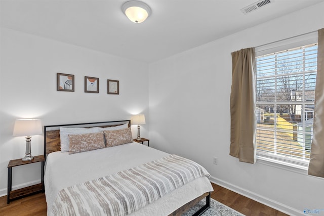 bedroom with wood finished floors, visible vents, and baseboards