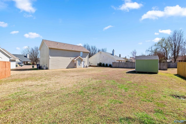 view of yard featuring an outbuilding, a storage shed, and fence