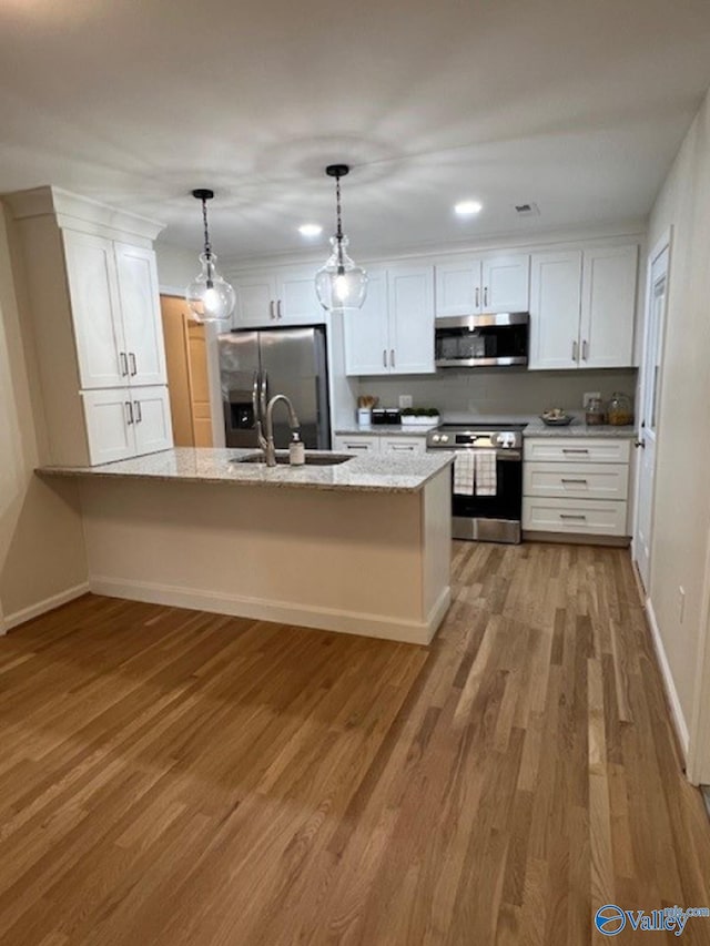 kitchen featuring a sink, white cabinetry, appliances with stainless steel finishes, and a peninsula