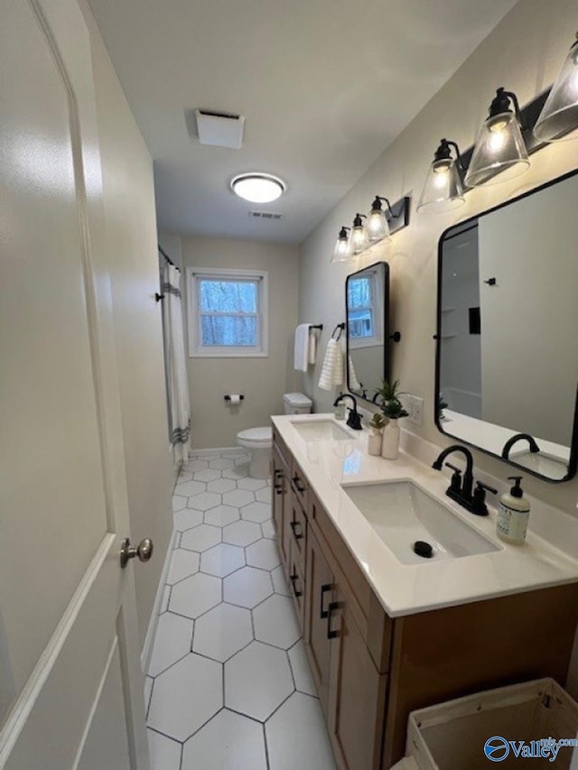 full bathroom featuring toilet, a sink, double vanity, and visible vents