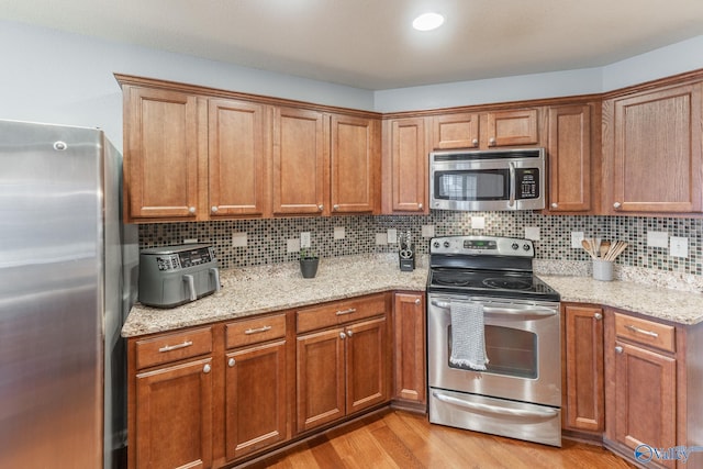 kitchen with decorative backsplash, light stone counters, and appliances with stainless steel finishes