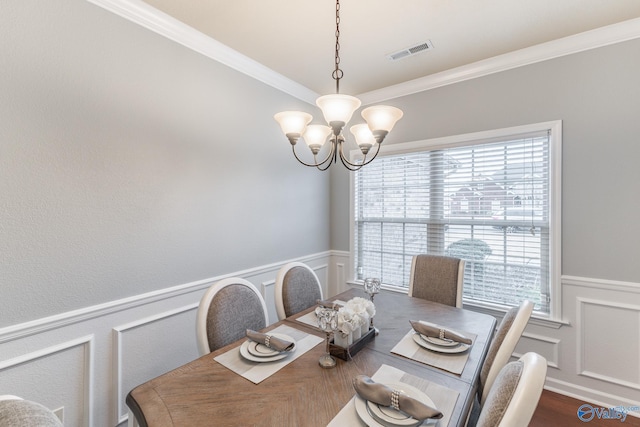 dining space with hardwood / wood-style flooring, ornamental molding, and a notable chandelier