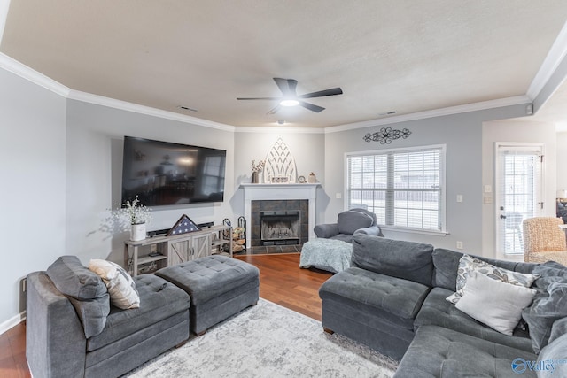 living room with ceiling fan, a fireplace, ornamental molding, and hardwood / wood-style flooring