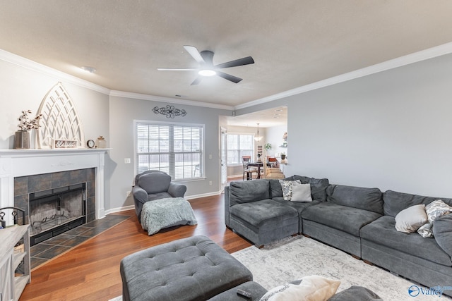 living room with ceiling fan, wood-type flooring, a fireplace, and ornamental molding