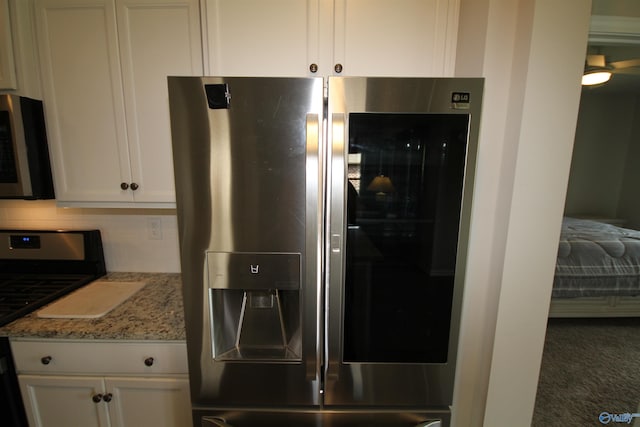 kitchen featuring backsplash, stainless steel appliances, white cabinets, and light stone counters