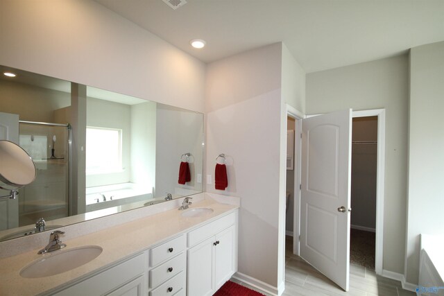 full bathroom with double vanity, a sink, and a stall shower