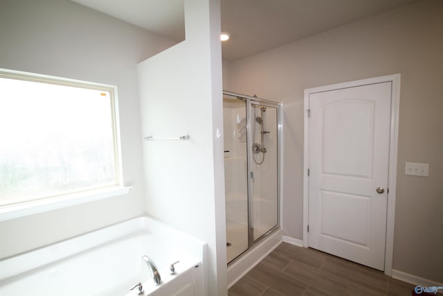 full bathroom featuring baseboards, a stall shower, a garden tub, and wood finished floors