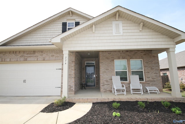 view of front of house featuring a garage, concrete driveway, a porch, and brick siding