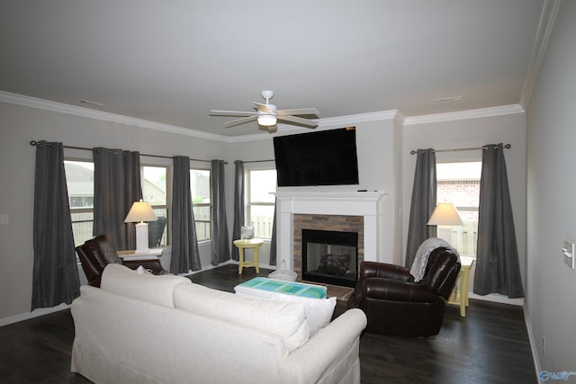 living area featuring baseboards, a ceiling fan, crown molding, and a stone fireplace