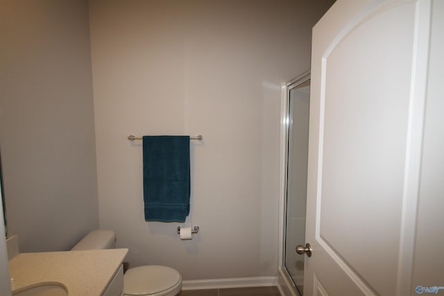 bathroom featuring vanity, toilet, baseboards, and a stall shower
