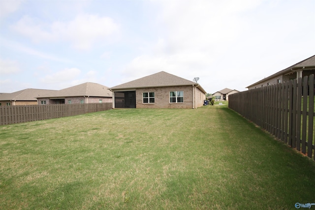 back of house with fence private yard, a lawn, and brick siding