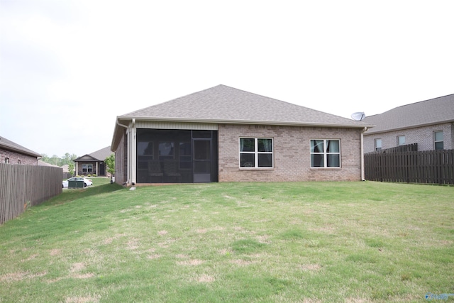 back of property with a yard, brick siding, and fence