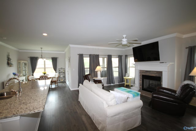living room with a ceiling fan, crown molding, a fireplace, dark wood-style floors, and recessed lighting
