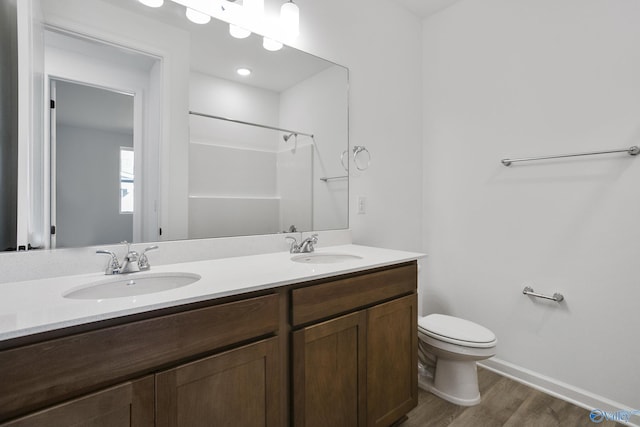 bathroom featuring hardwood / wood-style flooring, vanity, toilet, and a shower