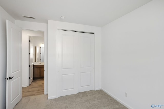 unfurnished bedroom featuring light carpet and a closet